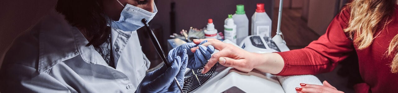 Nagelstyliste die gel aanbrengt op de nagels van een klant in een professionele salon, symbool voor veilige en conforme nagelbehandelingen volgens EU-regels. Nagelstyliste die gel aanbrengt op de nagels van een klant in een professionele salon, symbool voor veilige en conforme nagelbehandelingen volgens EU-regels.