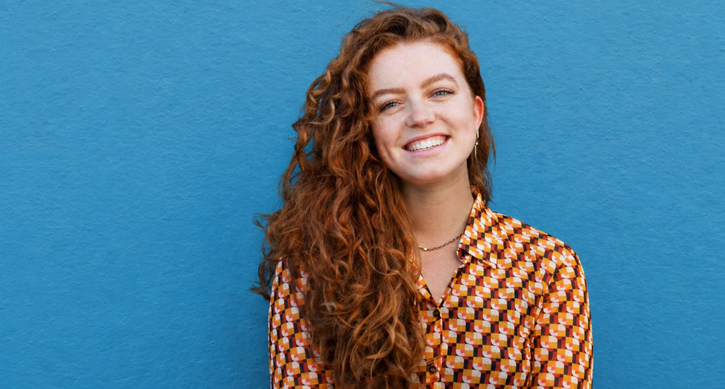 Long curly copper hairstyle with rich warm tones and natural texture.